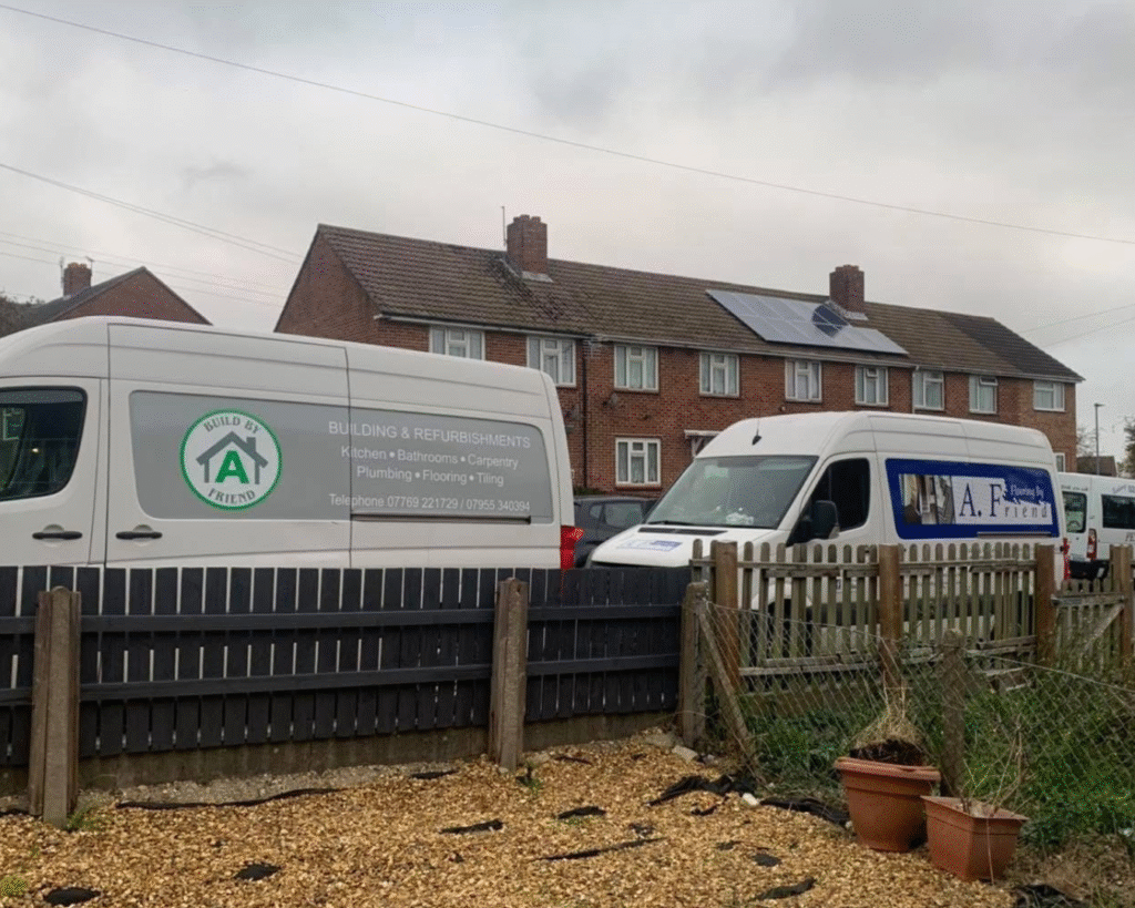 Two vans infront of a Hampshire house. One with the sign Build By A Friend and the other white transit with Flooring By A Friend.
